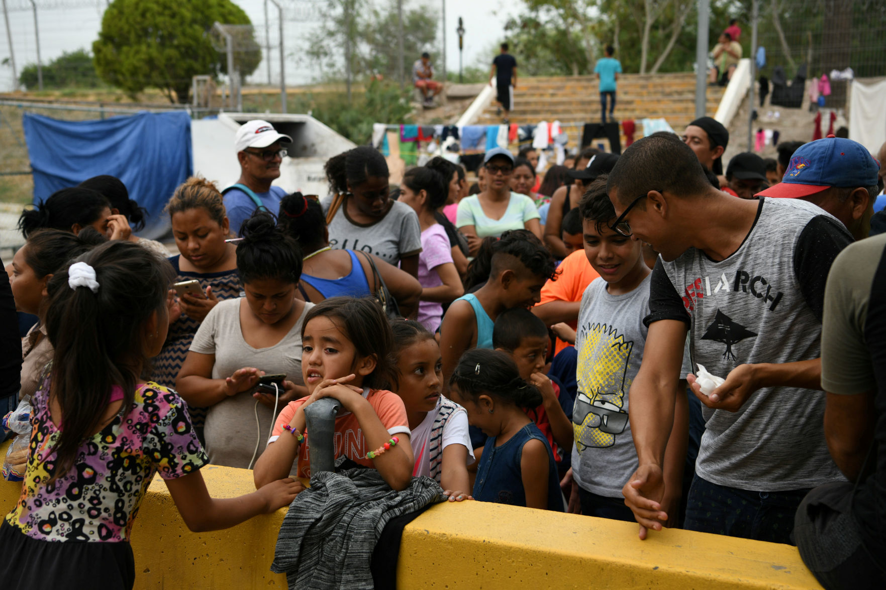 FILE PHOTO: Migrants, many of whom are asylum seekers sent back to Mexico from the U.S. under Migrant Protection Protocols (MPP), line up for a free meal provided by volunteers in Matamoros
